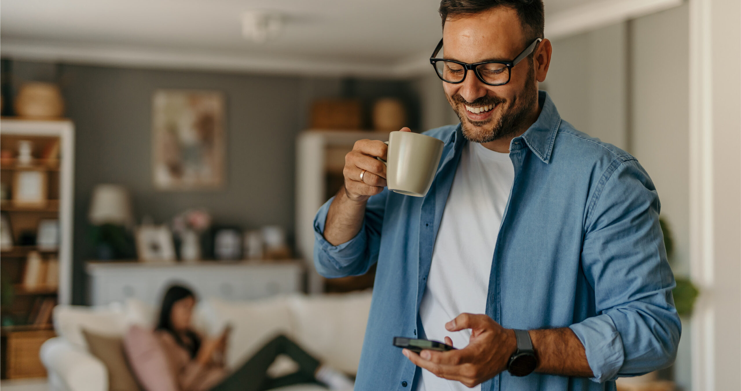 man checking credit score on phone before applying for mortgage while drinking morning coffee at home