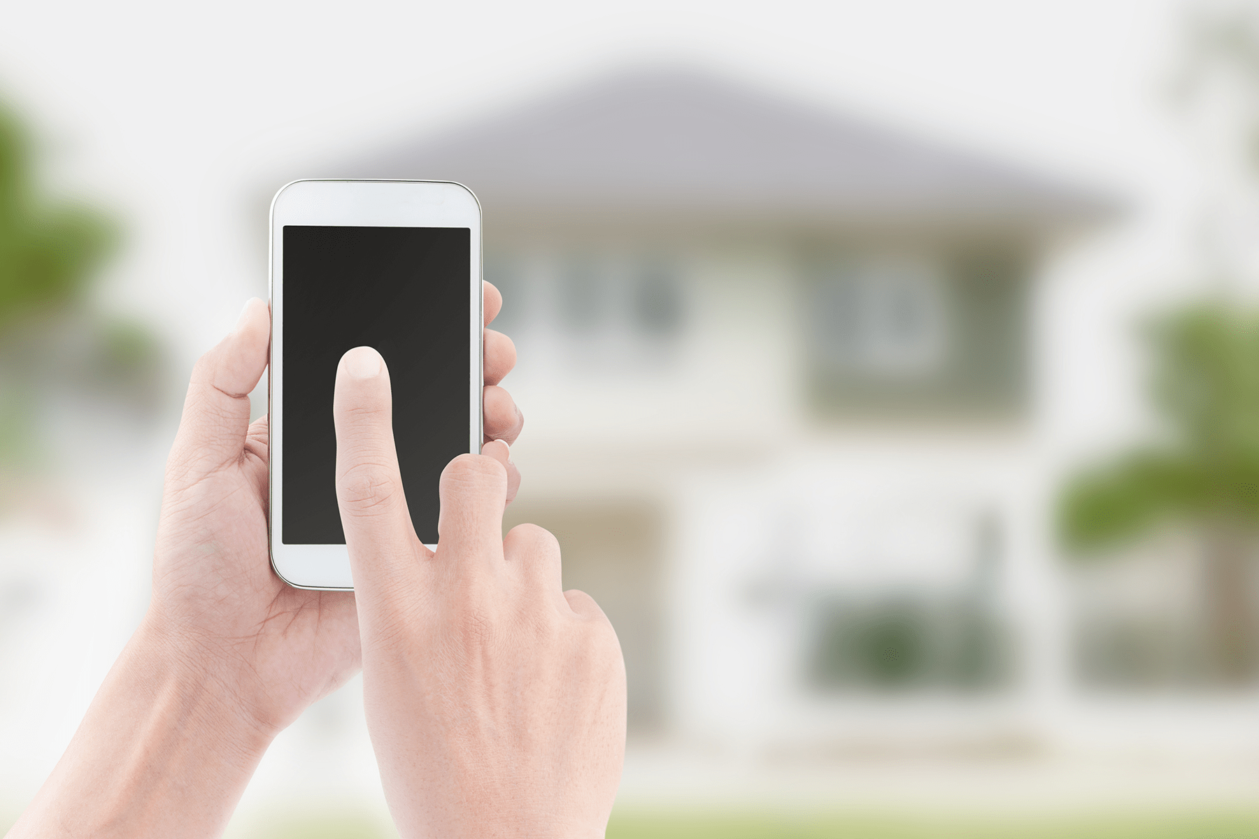 Feature image for 3 Steps To Selling Your Home With Social Media blog post - person using a smartphone in front of a house