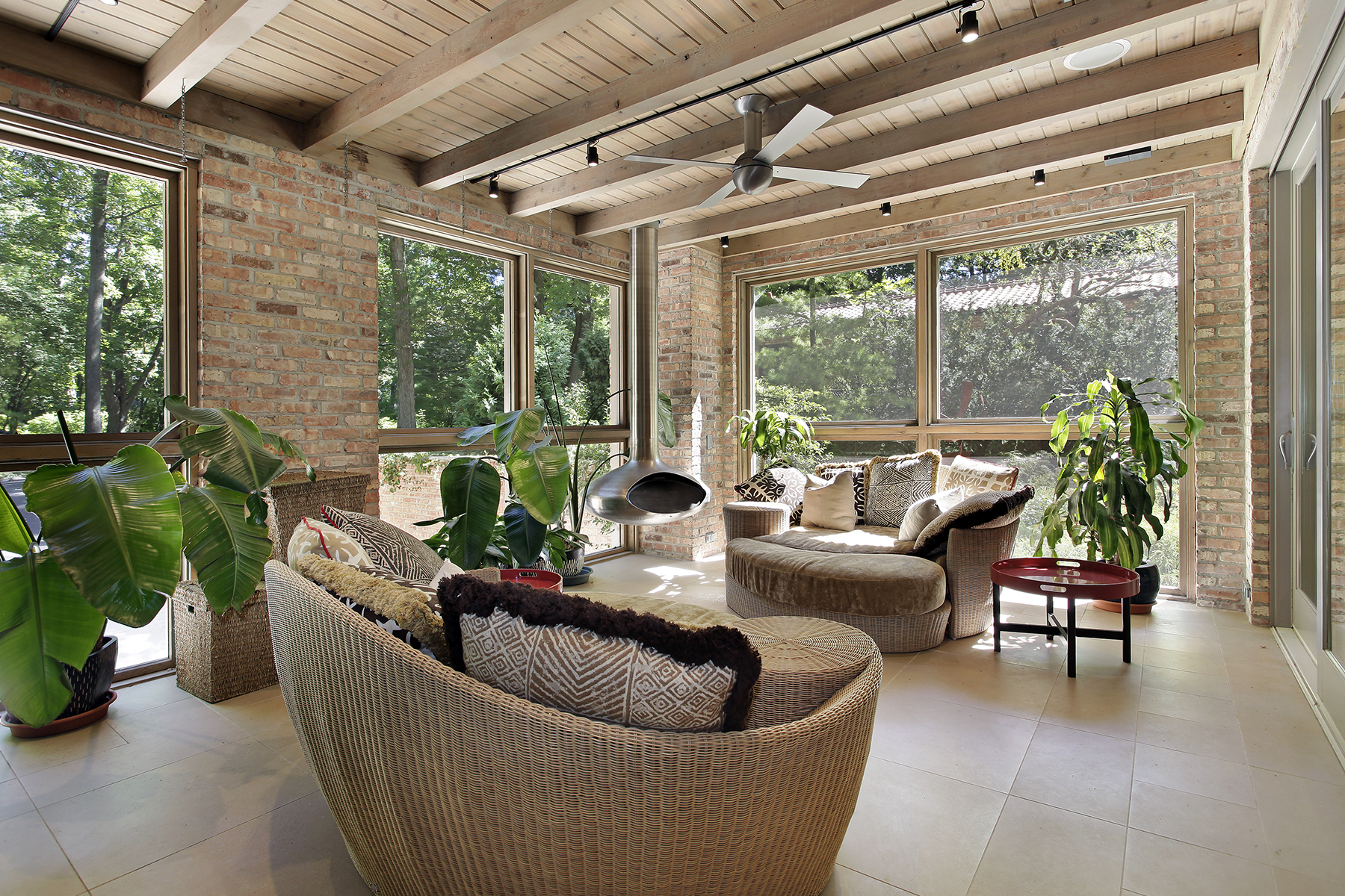 sunroom with exposed brick, plants and woven furniture