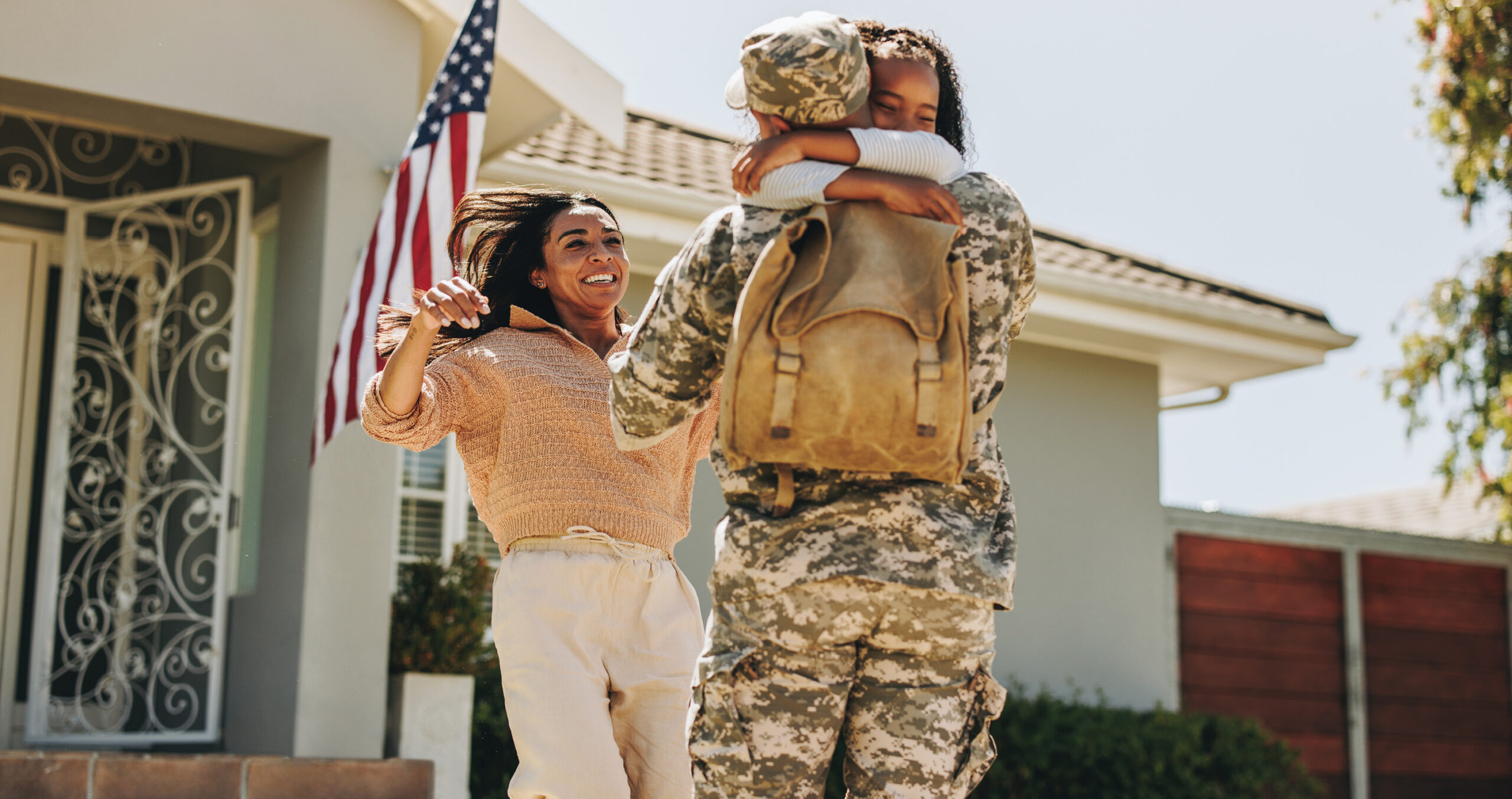 Mother and daughter greeting service member father as he returns home from deployment.