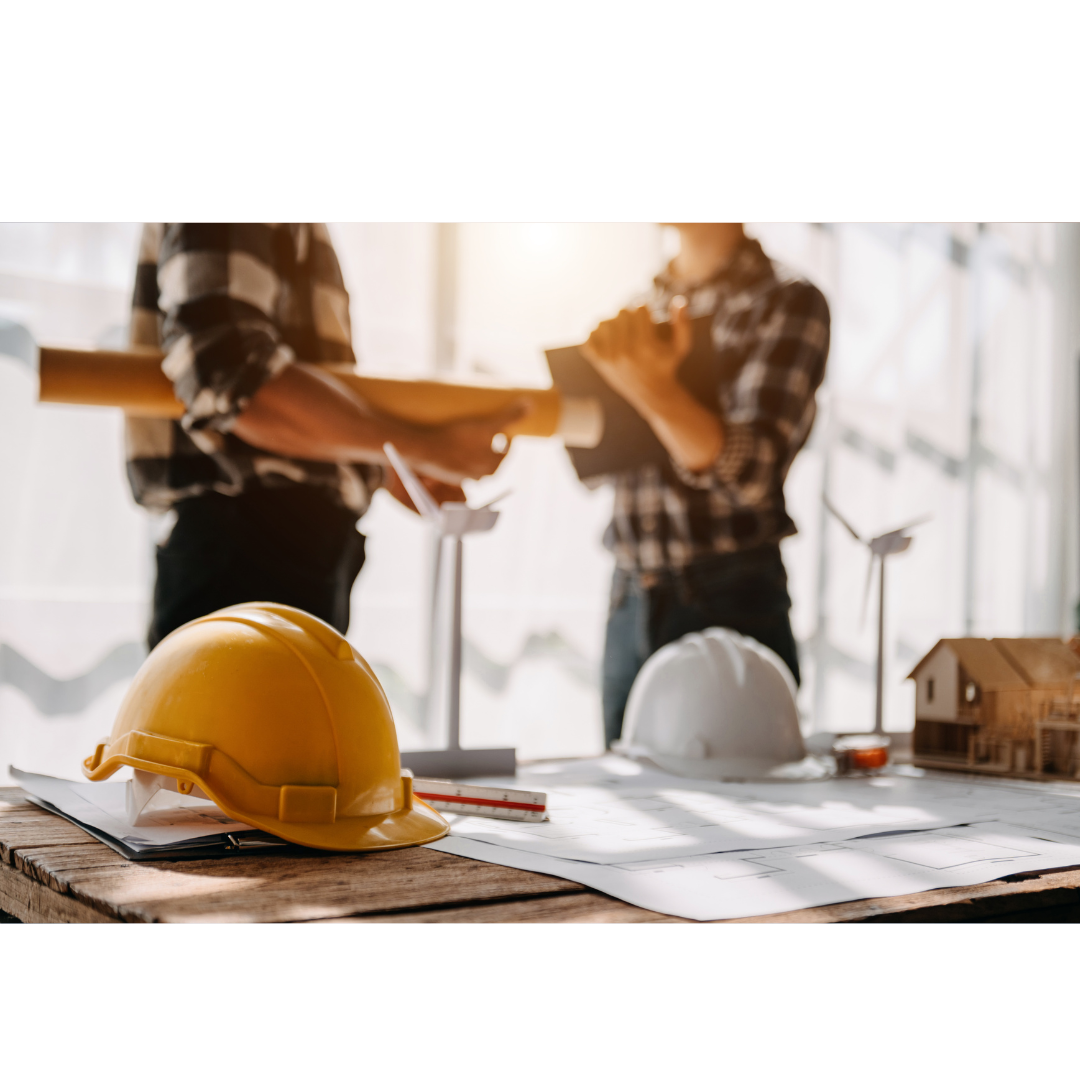 two workers in construction with hard hats and papers on table