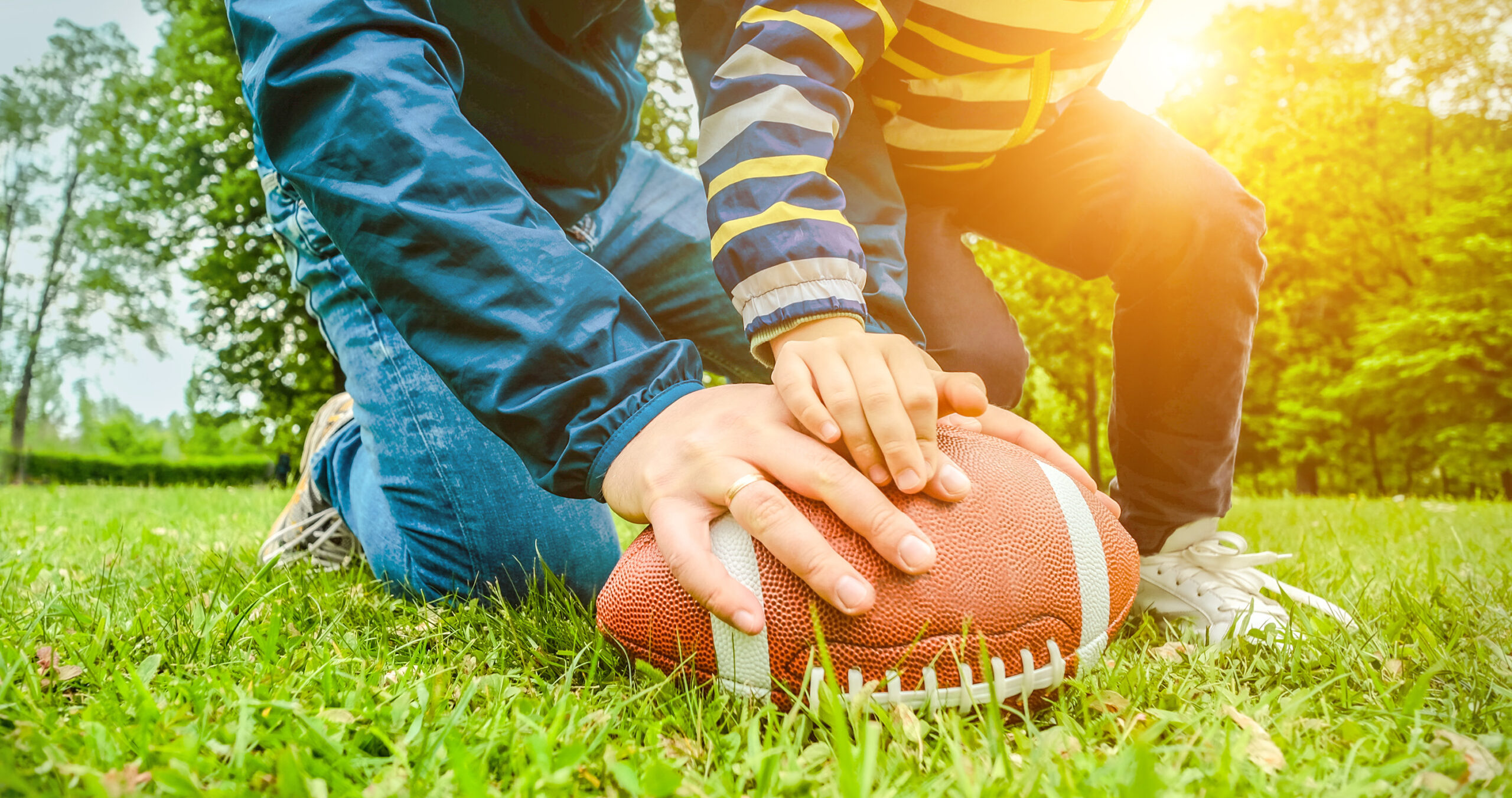 Father and son playing football on a sunny day.