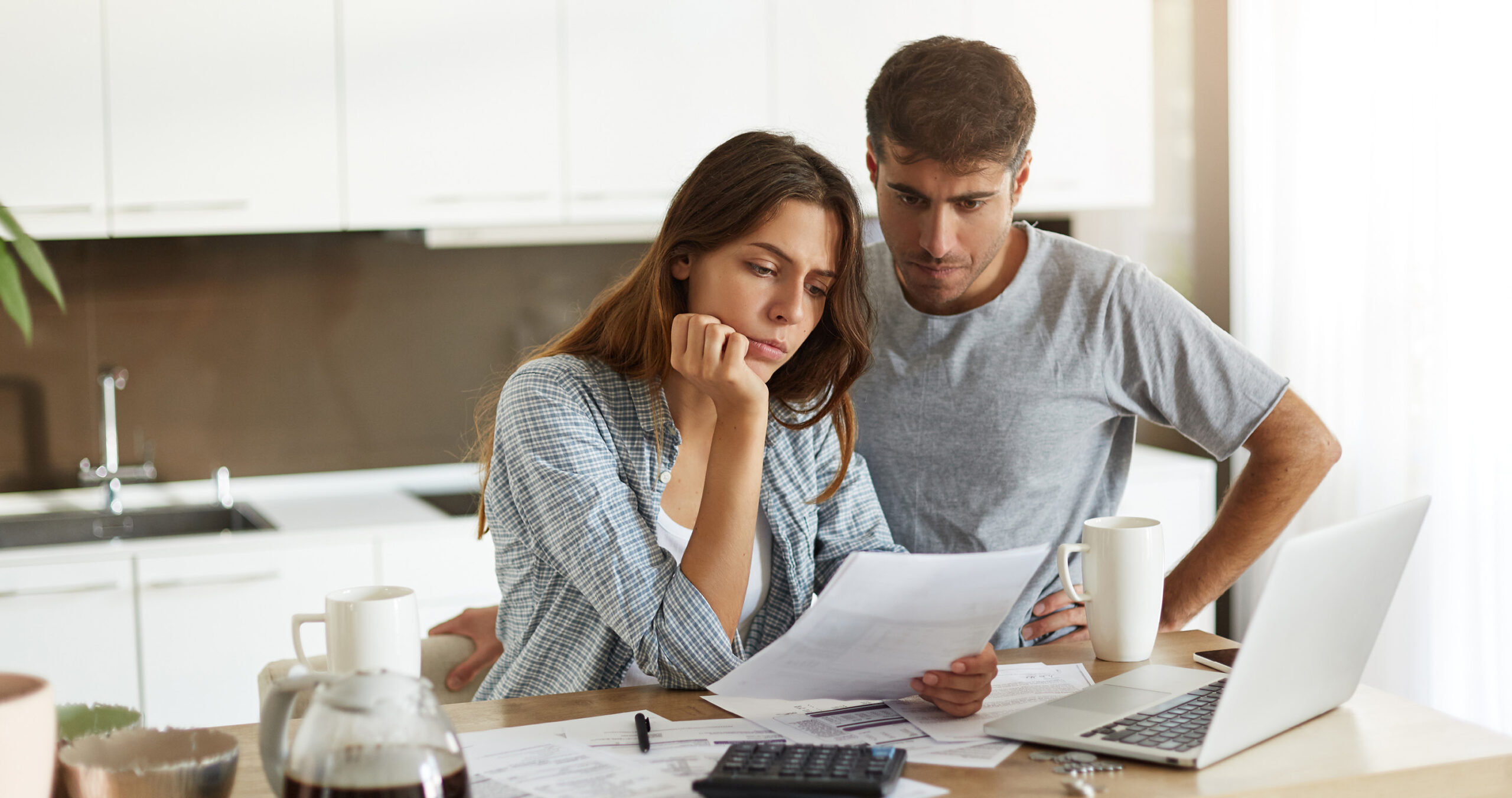 Couple reviewing mortgage statement and budget at kitchen table.